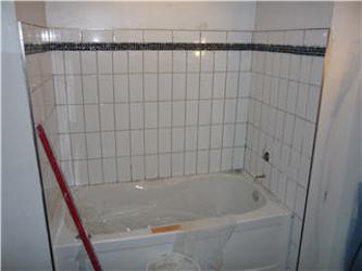 Bathtub and shower mid-renovation with white subway tile installation