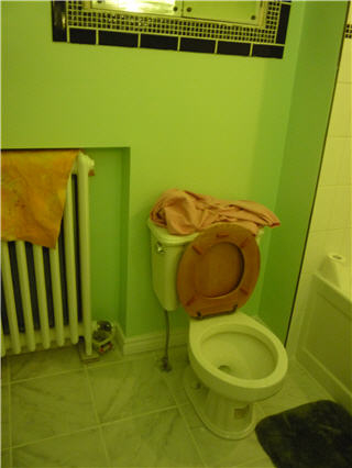 Finished bathroom with toilet, radiator, and tile floor